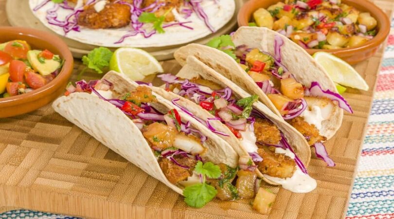 Baja-Fish-Tacos-Soft-shell-tacos-filled-with-seasoned-fried-white-fish-served-with-red-cabbage-pineapple-salsa-chunky-guacamole-and-creamy-Baja-style-sauce.