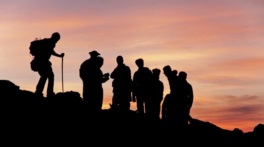 Sunset-silhouette-of-group-of-backpackers-hiking-at-the-top-of-a-mountain-with-a-pink-cloudy-dusk-sky-at-Pacaya-Volcano-Guatemala