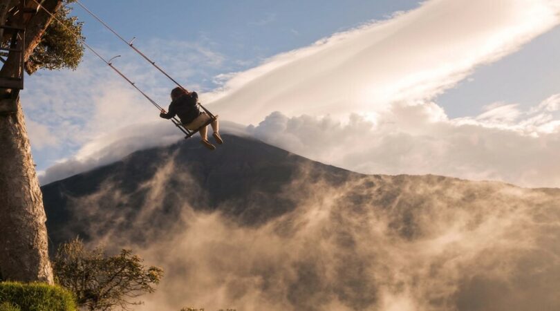 Banos De Agua Santa, Ecuador - 25 November Silhouette Of A Happy Tourist Girl Swinging On A Swing Above The Andes Mountains, Tungurahua Volcano In Background