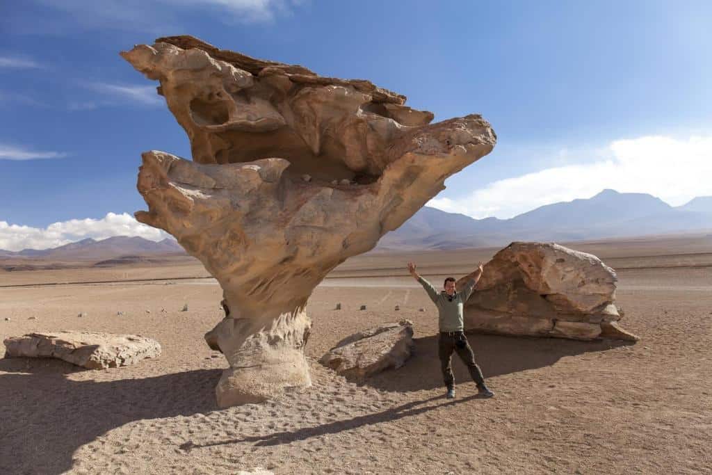 Young-man-standing-with-arms-outstretched-near-the-Stone-treem_Bolivia_Arbol-de-Piedra