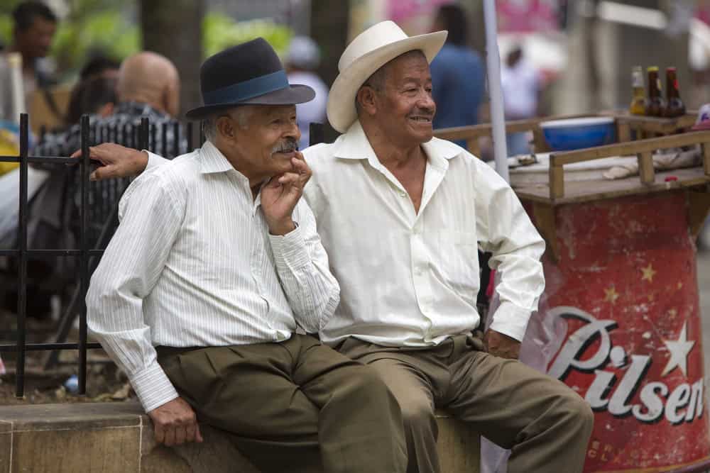 Portrait-of-senior-traditional-colombian-caucasian-men-with-hats-sitting-and-smiling-together-in-a-park-in-Medellin