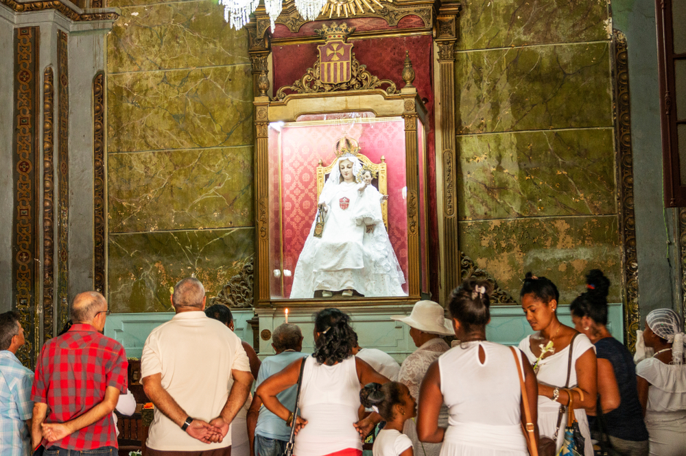 People-praying-lighting-candles-and-leaving-flowers-to-Madonna-in-a-Havana-Cuba