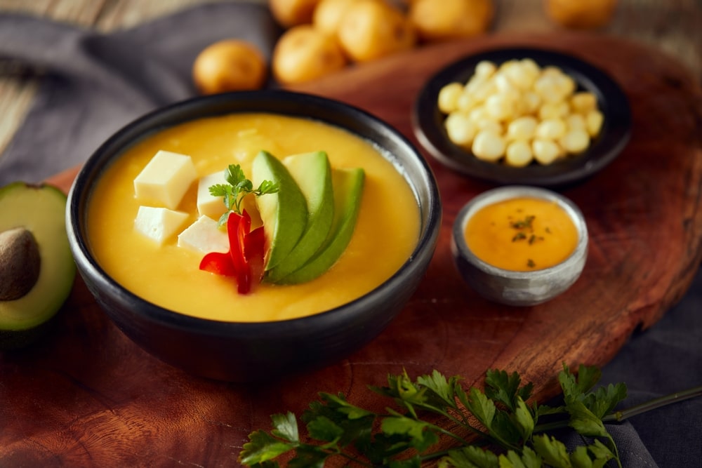 Ecuadorian locro de papa a traditional potato and cheese soup served with avocado and hominy.