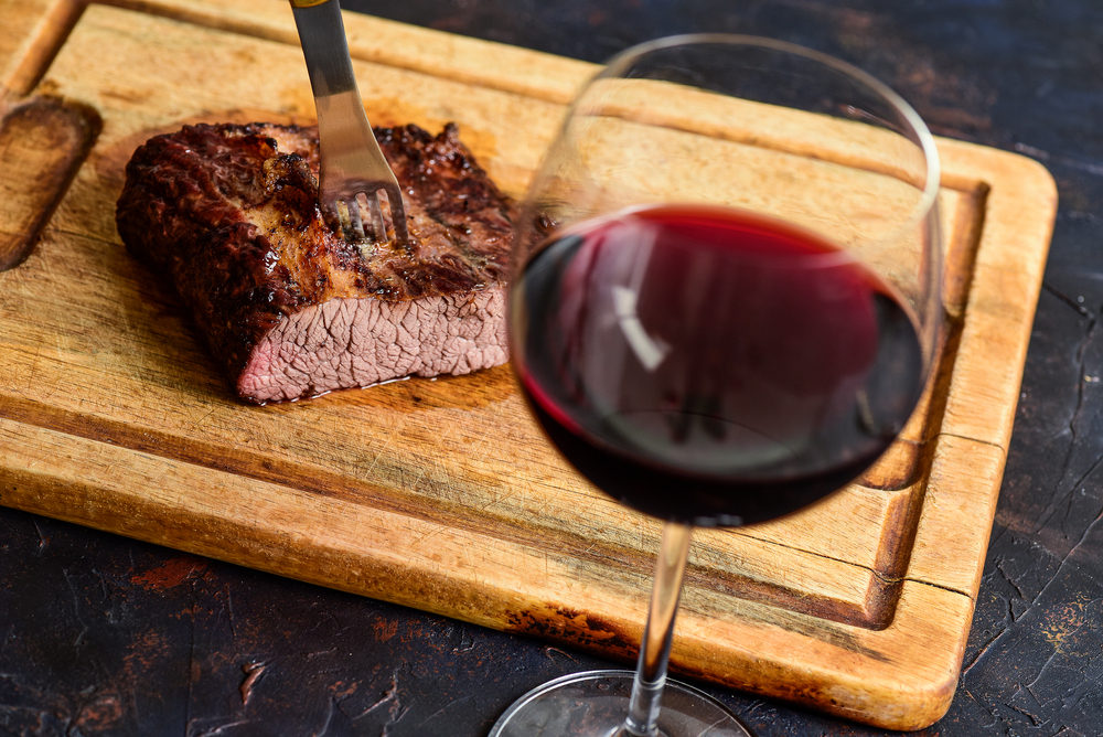 Roasted beef ribs with a glass of red wine presented on the table, traditional Argentine cuisine, Asado barbecue, Patagonia, 