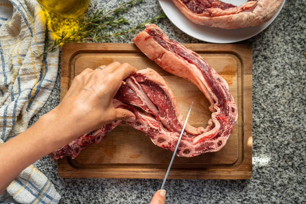 Top view of chef cutting raw short ribs to cook a typical argentinian asado. Barbecue concept.