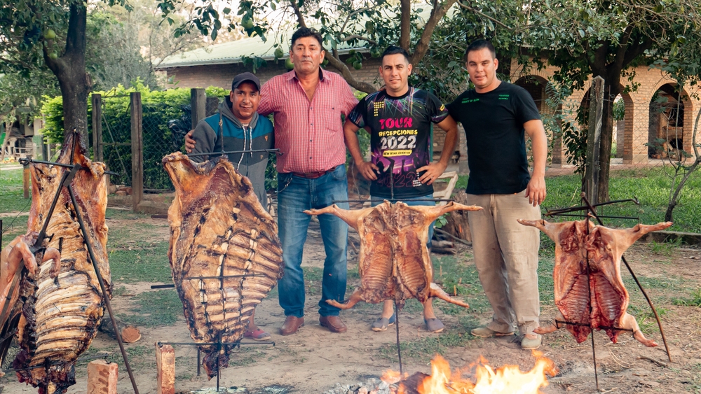 a group of friends and family prepare asado a la estaca during a family dinne